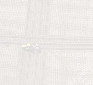 Aerial view of a woven pattern with a faint overlay, featuring yellow vehicles seemingly engaged in construction or maintenance. The pattern is light grey with intersecting linear designs.