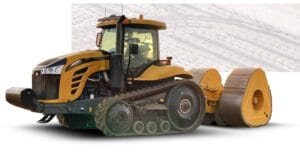 A large, yellow agricultural tractor with black tracks is attached to a compaction roller. The machinery is set on a white background.
