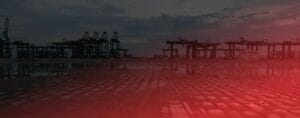 A port scene at dusk with silhouettes of large cranes against a cloudy sky. The foreground shows a wet, patterned surface reflecting a red illumination, creating a dramatic atmosphere.