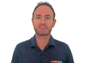 A man with short hair, wearing a dark blue polo shirt adorned with a "LANDPAC" logo, stands against a plain white background. Looking slightly off-camera, he seems to be about to share something important.