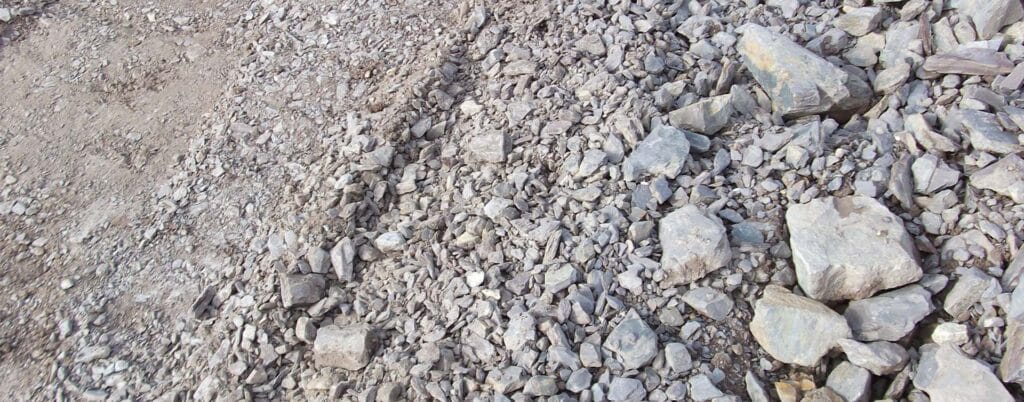 A close-up view of a rocky terrain, reminiscent of a demolition site, featuring various sizes and shapes of grey stones and gravel spread across the ground.