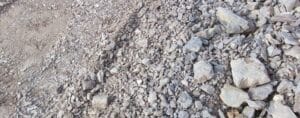 A close-up view of a rocky terrain, reminiscent of a demolition site, featuring various sizes and shapes of grey stones and gravel spread across the ground.