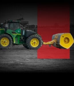 A green and yellow tractor with large tires is attached to a yellow industrial roller, parked on a dirt surface. The background is mostly black and white except for a red overlay behind the roller.