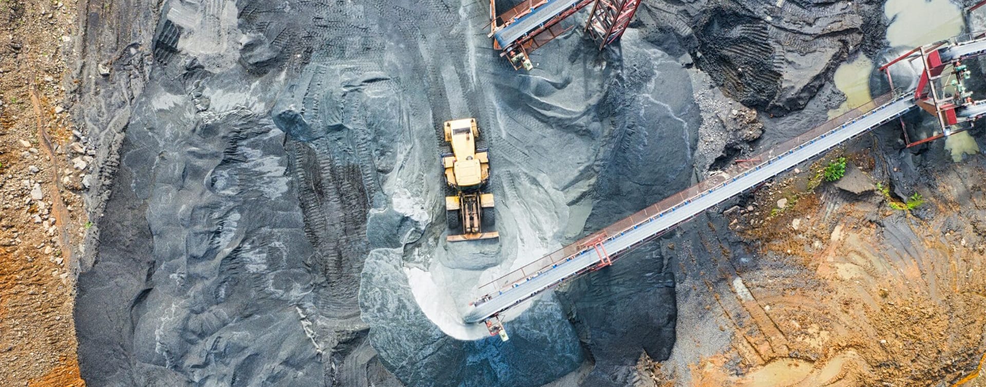 Aerial view of High-Energy Impact Compaction in Mining with excavator and conveyor belts.