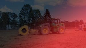Green tractor on a dirt field, trees behind, red light overlay; ideal for job reports or technical papers.